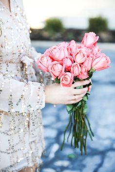 a woman holding a bouquet of pink roses