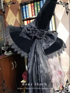 a black hat with roses and feathers on it sitting in front of a book shelf