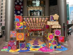 an artistic display in front of a building with colorful decorations on the floor and walls