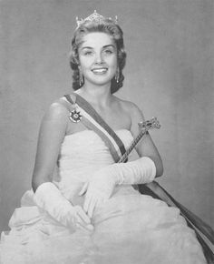 an old black and white photo of a woman wearing a tiara with gloves on