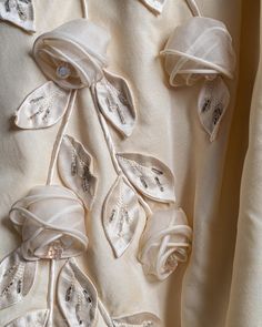 white fabric with flowers and leaves on it, as seen from the bottom down in close up