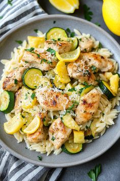 chicken and zucchini pasta on a plate with lemons