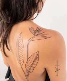 the back of a woman's shoulder with a cross and leaves tattoo on it