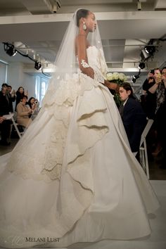 a woman in a wedding dress walking down the runway