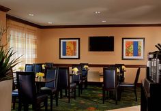 a dining room with tables and chairs in front of a flat screen tv mounted on the wall