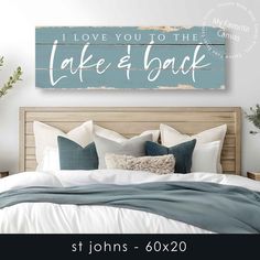 a bed with pillows and blankets in front of a wooden sign that says i love you to the lake and back