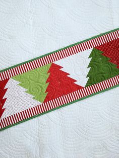 a quilted table runner with red, green and white christmas trees on the border