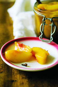 two pieces of fruit sitting on a plate next to a jar of jelly and bananas