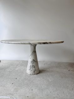 a white marble table sitting on top of a cement floor