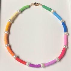 a multicolored beaded necklace with pearls and gold clasp on a white surface