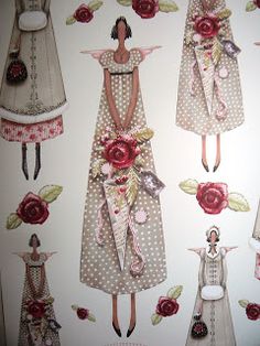 several paper dolls are hanging on the wall with roses and ribbons around them, as if they were made out of fabric