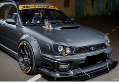 a gray subarun car parked on the side of the road in front of a building