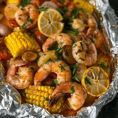 shrimp and corn on the cob in foil with lemon wedges, parsley