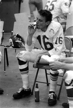 two football players are sitting on chairs and one is taking a bite out of something