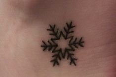 a small snowflake tattoo on the side of a woman's ribcage