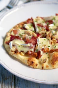 a small pizza with bacon and cheese on a white plate