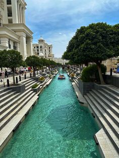 there are many steps that lead up to the water in this city canal, which is lined with trees and people