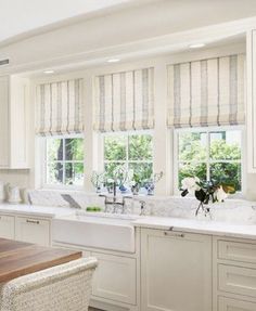 a kitchen with white cabinets and marble counter tops, along with an island in the middle