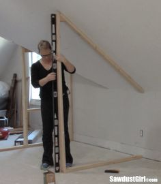 a woman standing in front of a mirror holding a large piece of wood on top of it