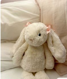 a white stuffed rabbit sitting on top of a bed