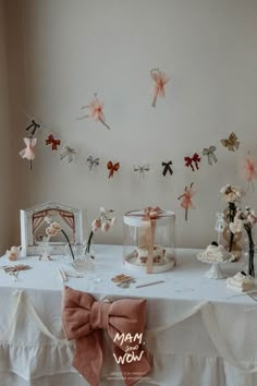 a white table topped with lots of decorations and pink bow tie hanging from the ceiling