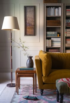 a living room filled with furniture and a lamp on top of a wooden table next to a bookshelf