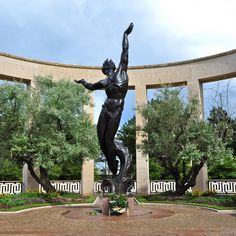 there is a statue in the middle of a circular area with trees and bushes around it