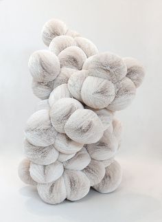 a pile of white balls sitting on top of each other in front of a white wall