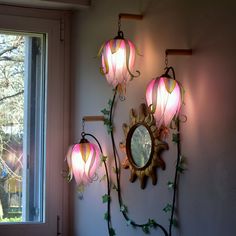 three pink lamps are hanging on the wall next to a window with a mirror in it