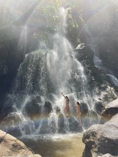 two people are jumping into the water from a waterfall