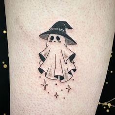 a small black and white tattoo of a ghost wearing a witches hat with stars around it