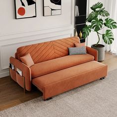 an orange couch sitting on top of a wooden floor next to a potted plant