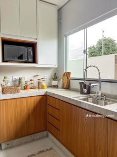 a kitchen with wooden cabinets and white counter tops next to a window that looks out onto the backyard