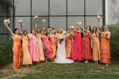 a group of women standing next to each other holding bouquets in front of a building