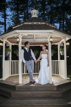 a bride and groom holding hands under a gazebo