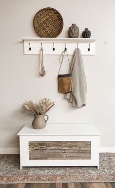 a white bench sitting under a wall mounted coat rack