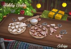 a wooden table topped with lots of cookies and icing next to a christmas tree