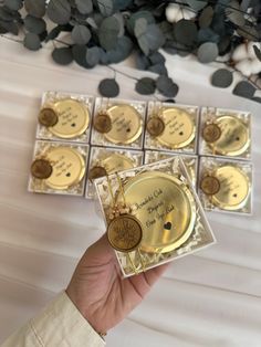 a person holding up some gold discs with writing on them in front of a white table