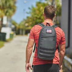 a man walking down the street with a backpack on his back and an american flag sticker on it