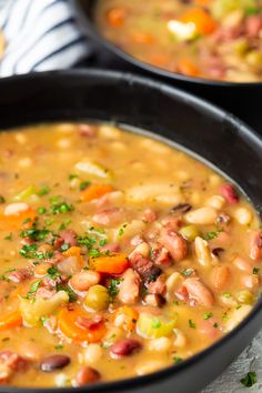 two black pans filled with soup on top of a table