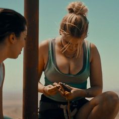 two women sitting on the ground looking at their cell phones