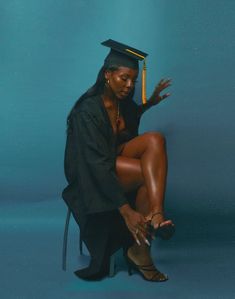 a woman in a graduation cap and gown sitting on a chair with her legs crossed