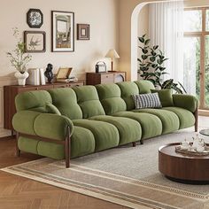 a living room with green couches and pictures on the wall above it, along with a coffee table