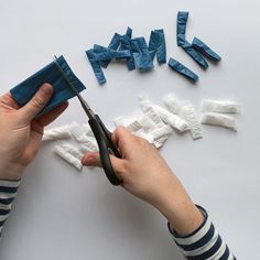 someone using scissors to cut up pieces of paper with strips of blue tape on them