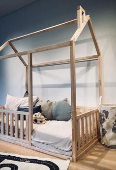 a bed with a wooden frame and mattress on the floor in front of a blue wall