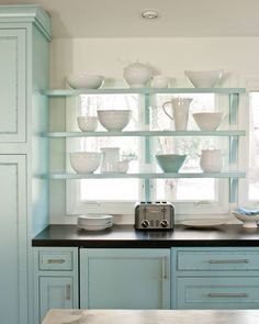 a kitchen with blue cabinets and white dishes