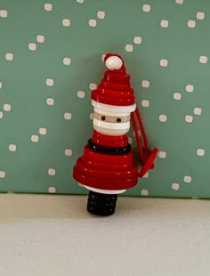 a red and white christmas decoration with a santa clause on it's head in front of a green polka dot wall