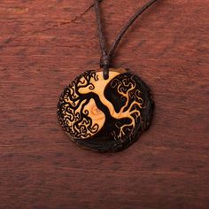 a black and white pendant with a tree on it sitting on a wooden table next to a string