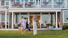 two women are walking in front of a house with an american flag on the balcony