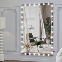 a living room with a large mirror on the wall and lights in front of it